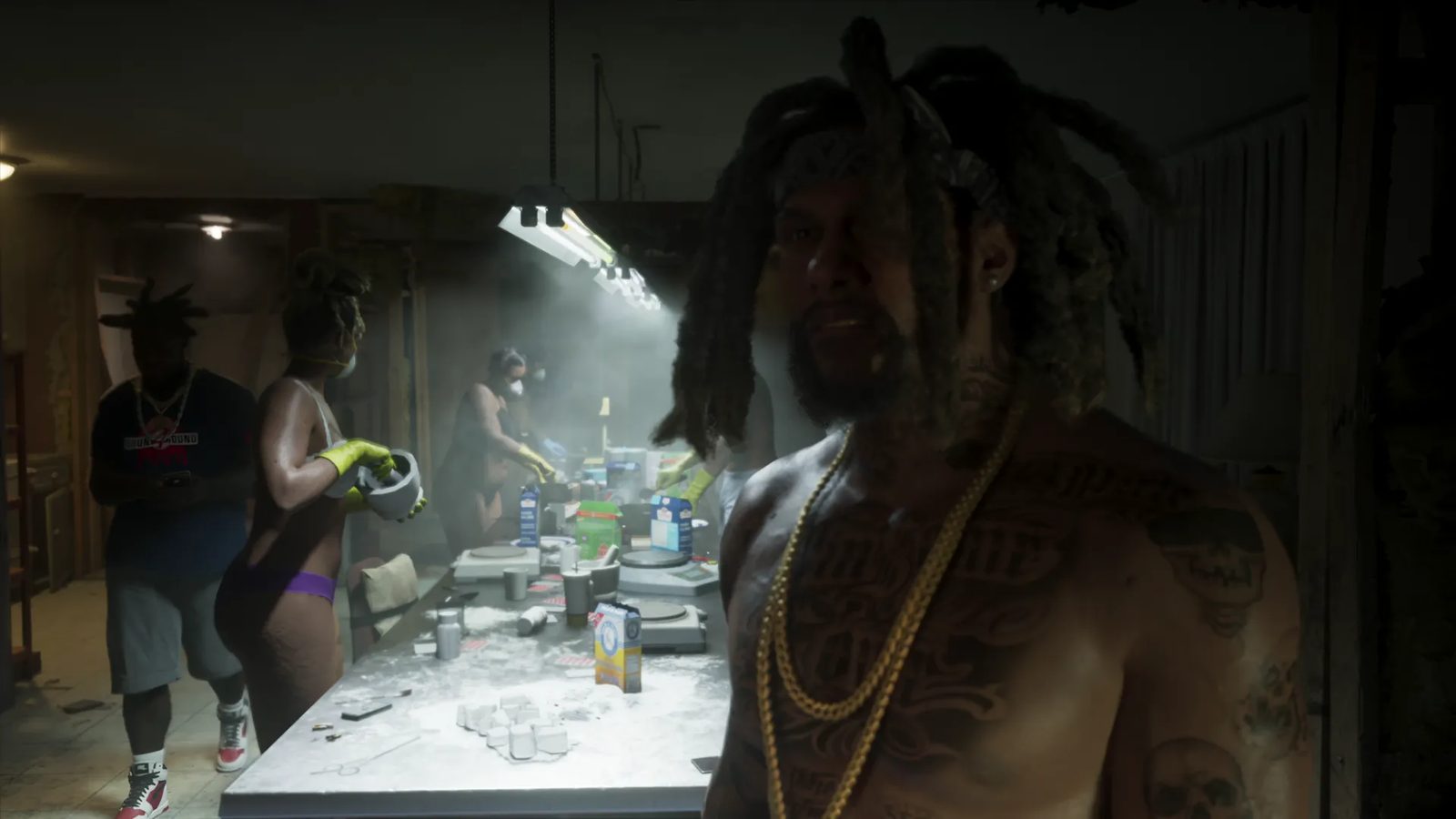 A shirtless, tattooed man with dreadlocks and gold chains stands in a dim room where masked workers process white powder at a long table.
