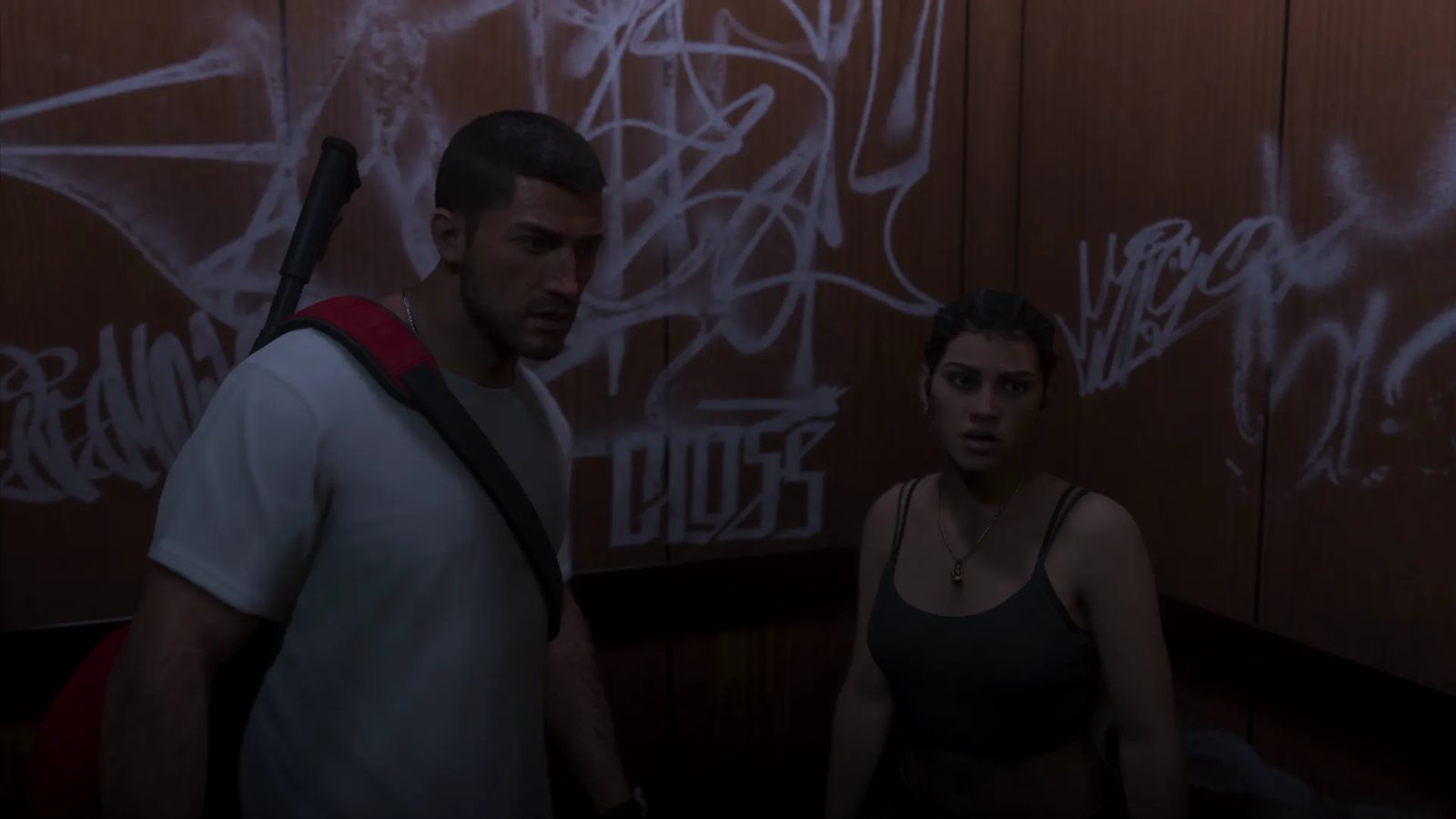 Jason Duval and Lucia Caminos stand side by side in a dimly lit lift with graffiti-covered wooden walls, both looking tense.