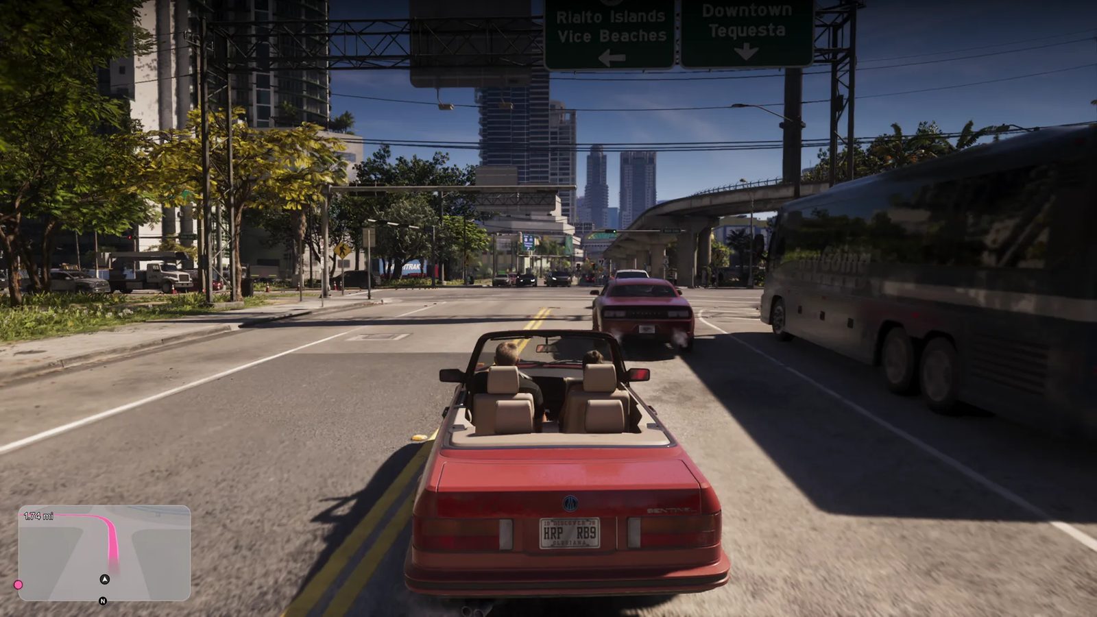 A red convertible with two occupants drives along a sunny city road past a red muscle car and a dark coach, beneath green signs for Downtown Tequesta.