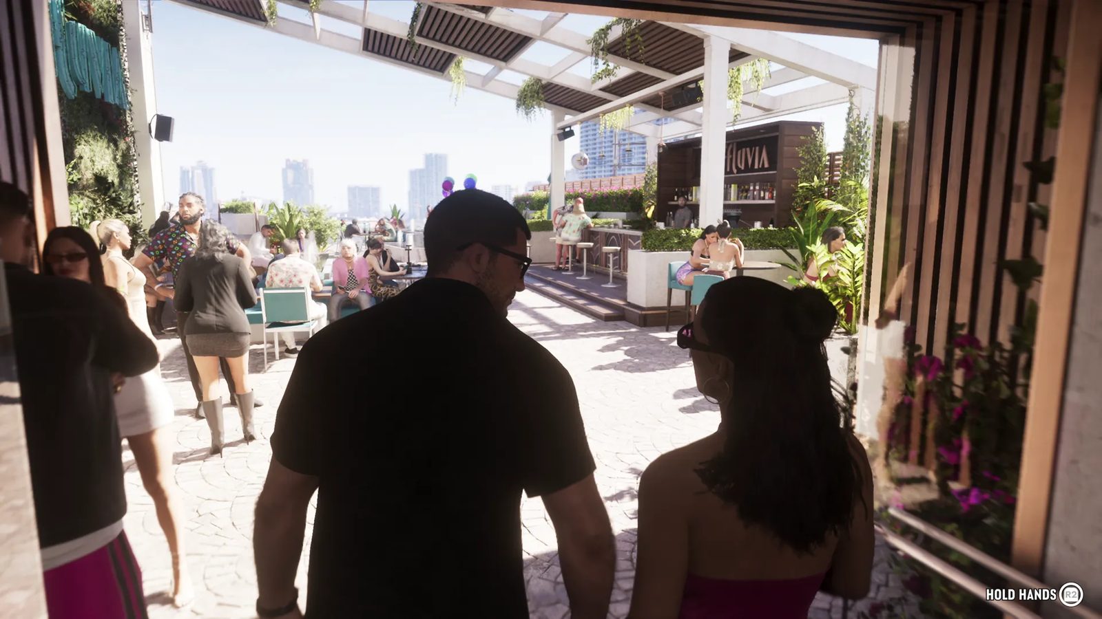A man in a black shirt and sunglasses and a woman with dark hair walk onto a sunny rooftop bar, with the Effluvia sign and city skyline ahead.