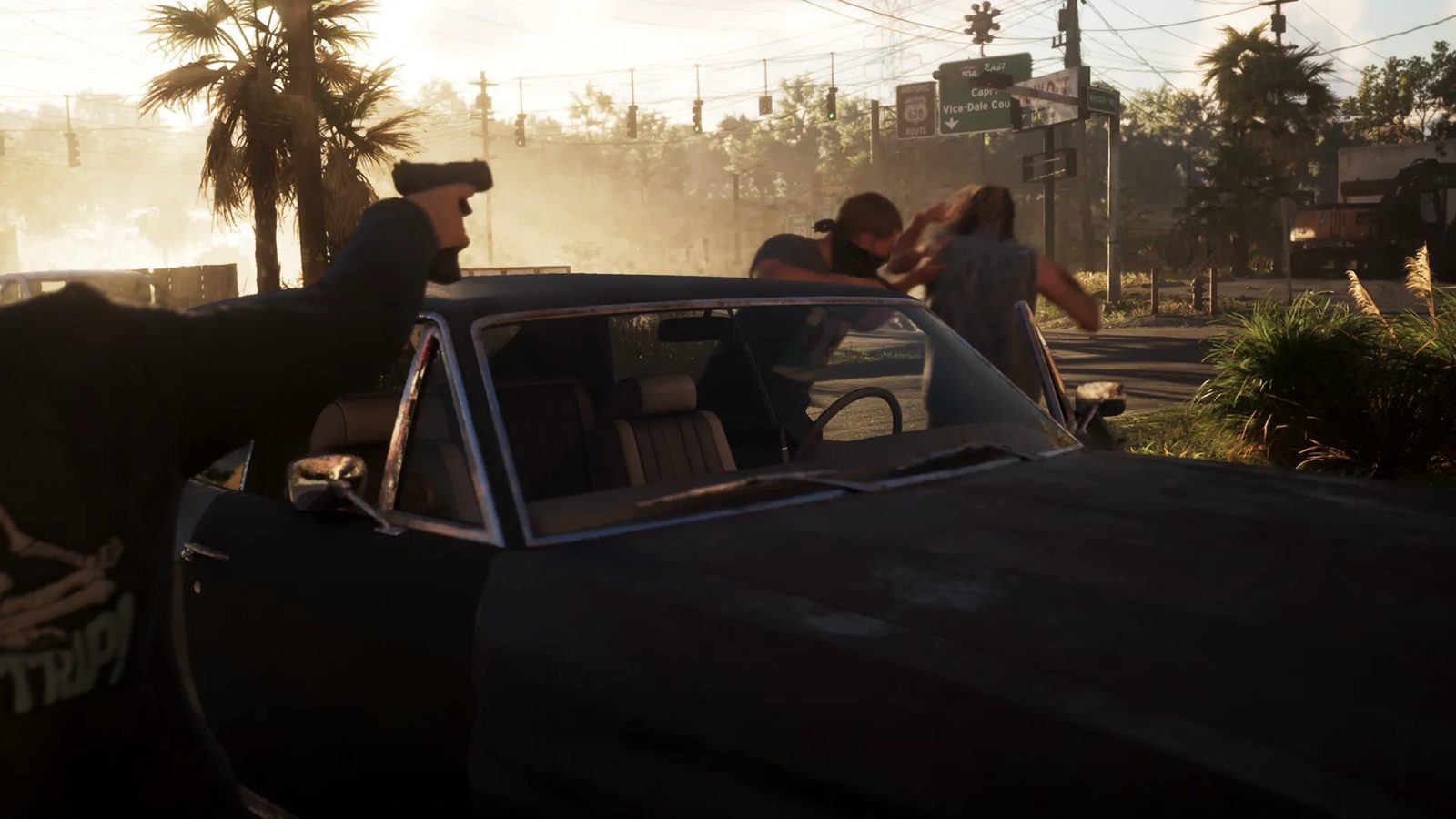 A masked man and another person scuffle behind a dark Declasse Tulip while a gun is aimed from the left, on a sunlit road junction lined with palm trees.