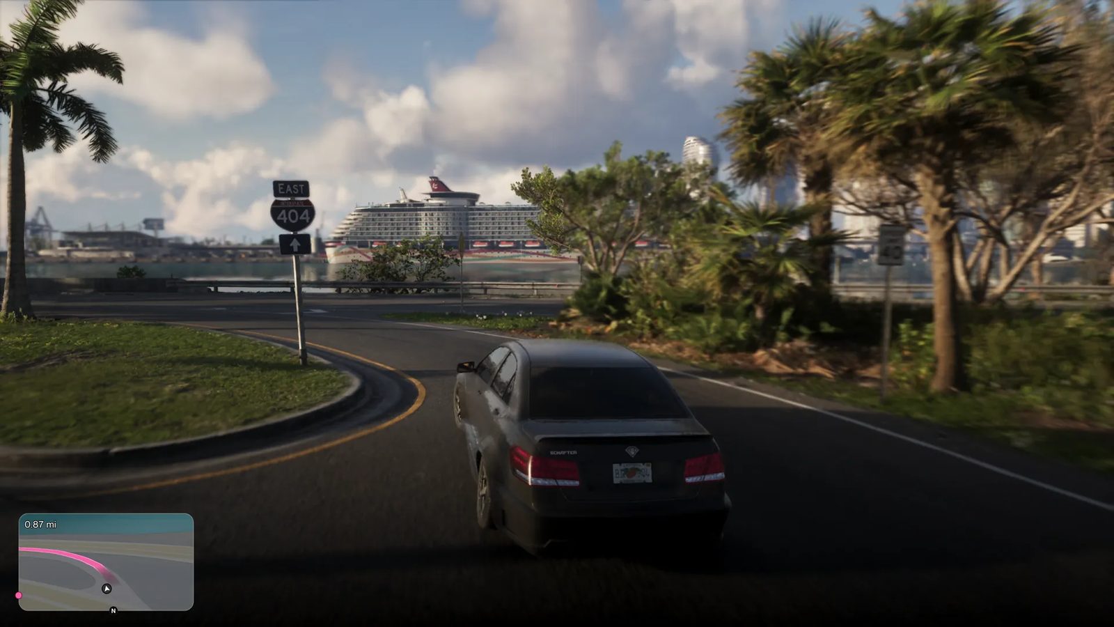 A dark grey Benefactor Schafter V12 takes a curving road past palm trees, with a large cruise ship moored across the water behind it.