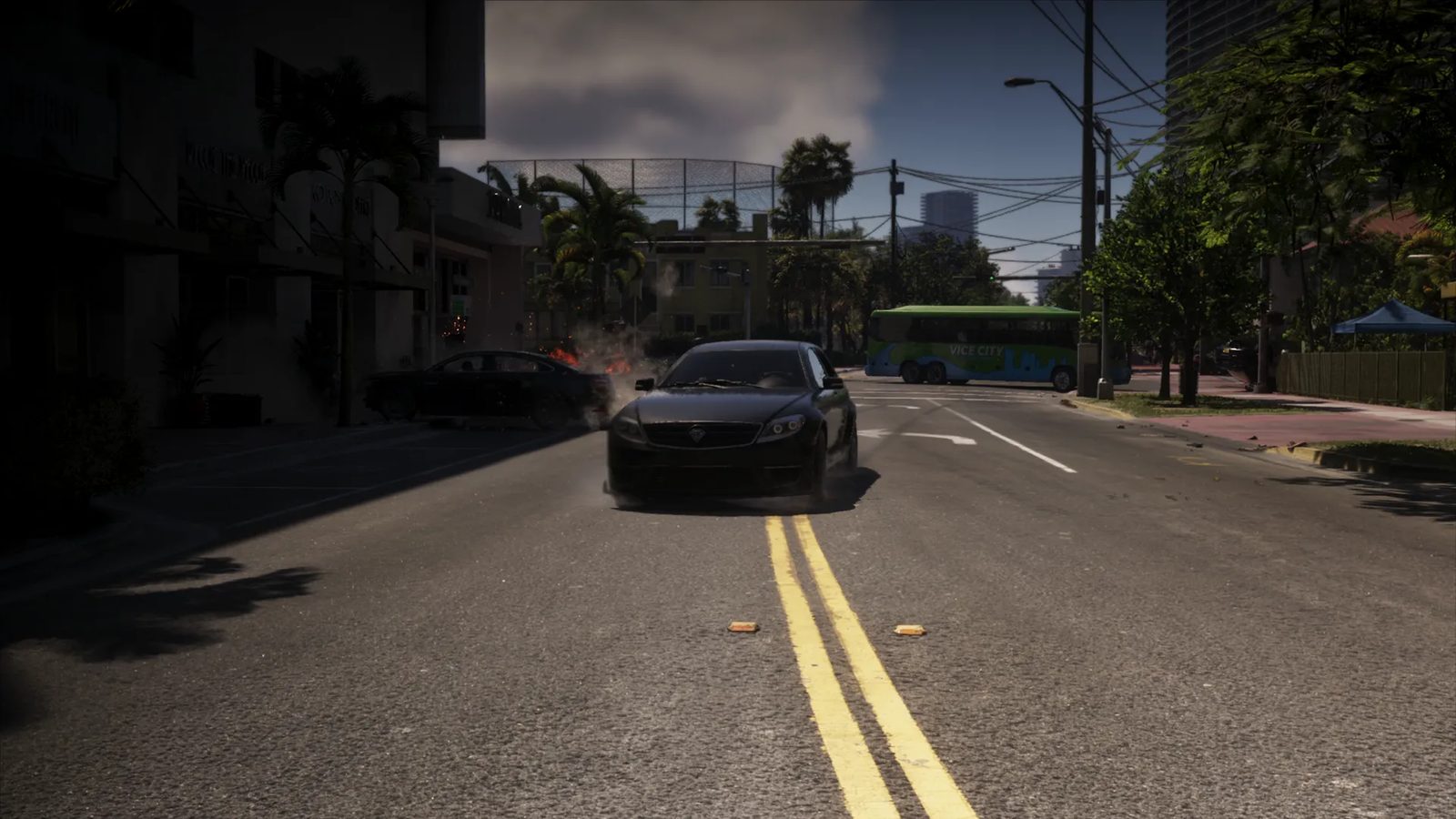 A black Benefactor Schafter V12 speeds down a Vice City street past a burning wreck, with a green Dashound bus ahead.