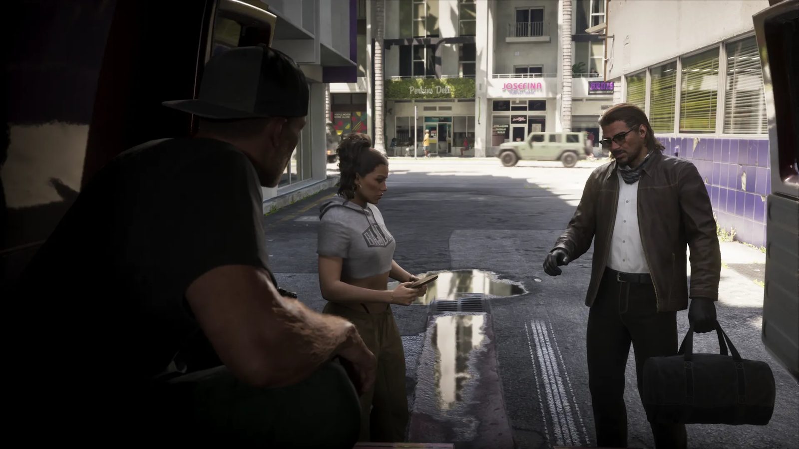A woman in a grey cropped hoodie looks at a phone between a man in a cap and a bearded man in a leather jacket, on a sunlit city street.