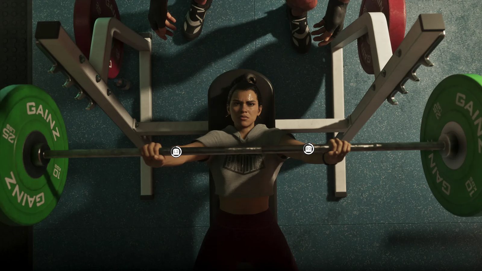 Lucia Caminos grimaces as she bench presses a barbell with green GAINZ weight plates, seen from directly above in a gym.
