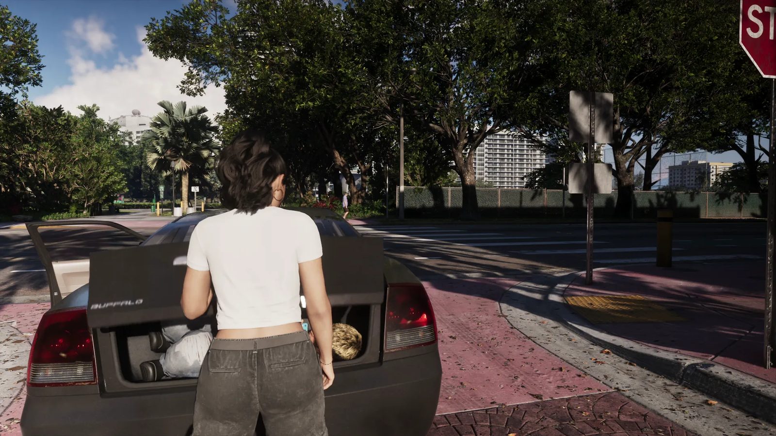 A woman in a white t-shirt stands at the open boot of a dark Bravado Buffalo on a sunlit street corner, with two people inside the boot.