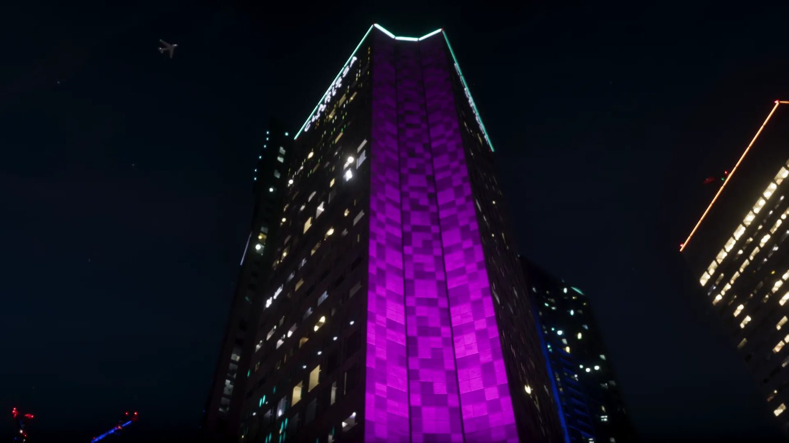 A tall skyscraper lit with a purple checkerboard pattern towers over the viewer at night, with a small jet in the dark sky.
