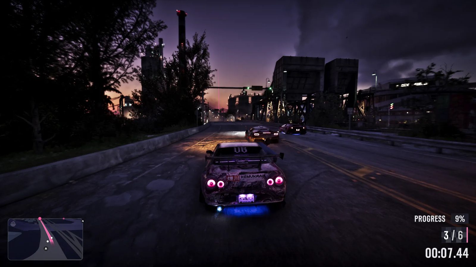 A purple-lit tuned sports car with a rear wing and blue underglow races two other cars along a road at dusk towards an industrial plant.