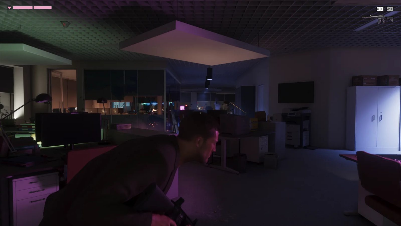 Jason Duval crouches with a rifle behind office desks in a dark, open-plan office lit in purple and green.
