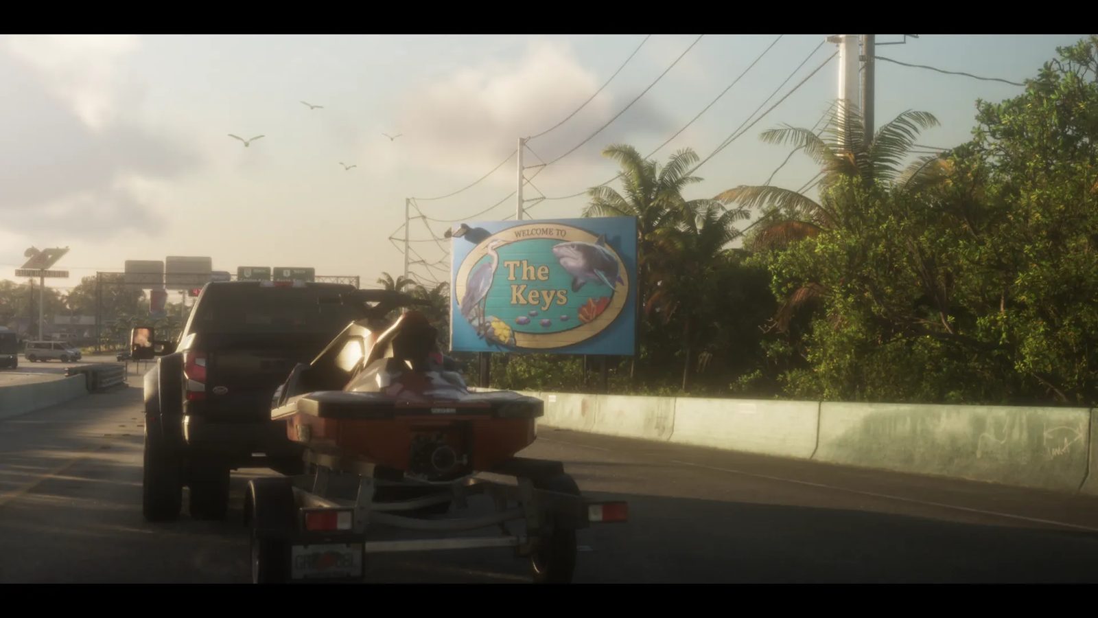 A dark pickup truck tows an orange jet ski on a trailer along a coastal road past a blue sign reading "Welcome to The Keys", with palm trees and gulls.