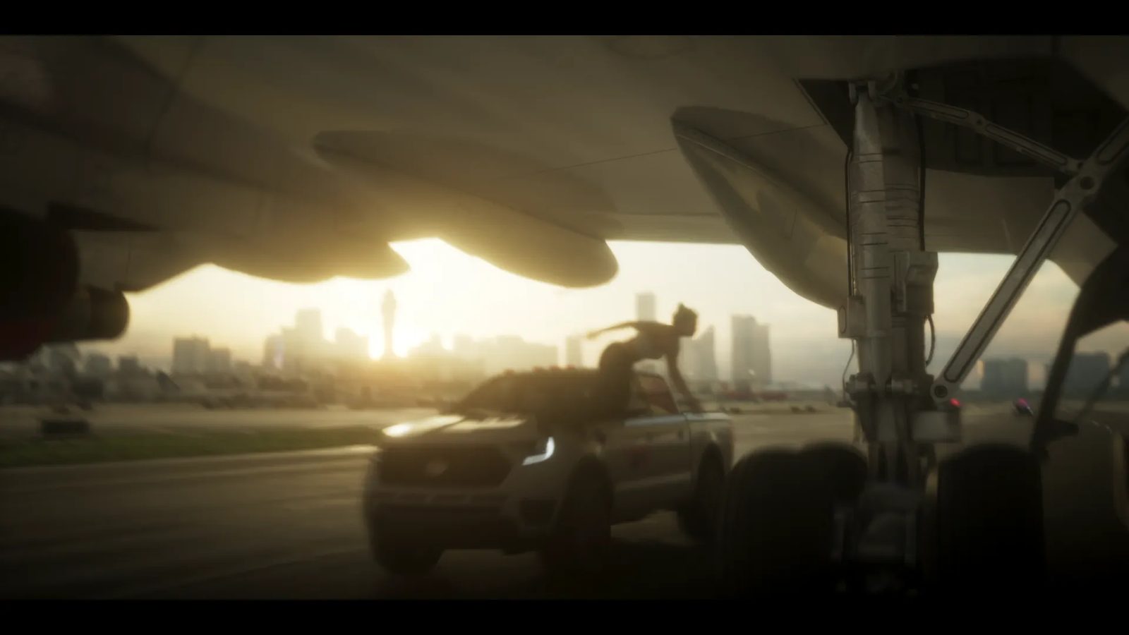 A woman leaps onto a silver pickup truck on an airport runway, seen from under a plane's wing and landing gear, with a city skyline in the sunset glow.