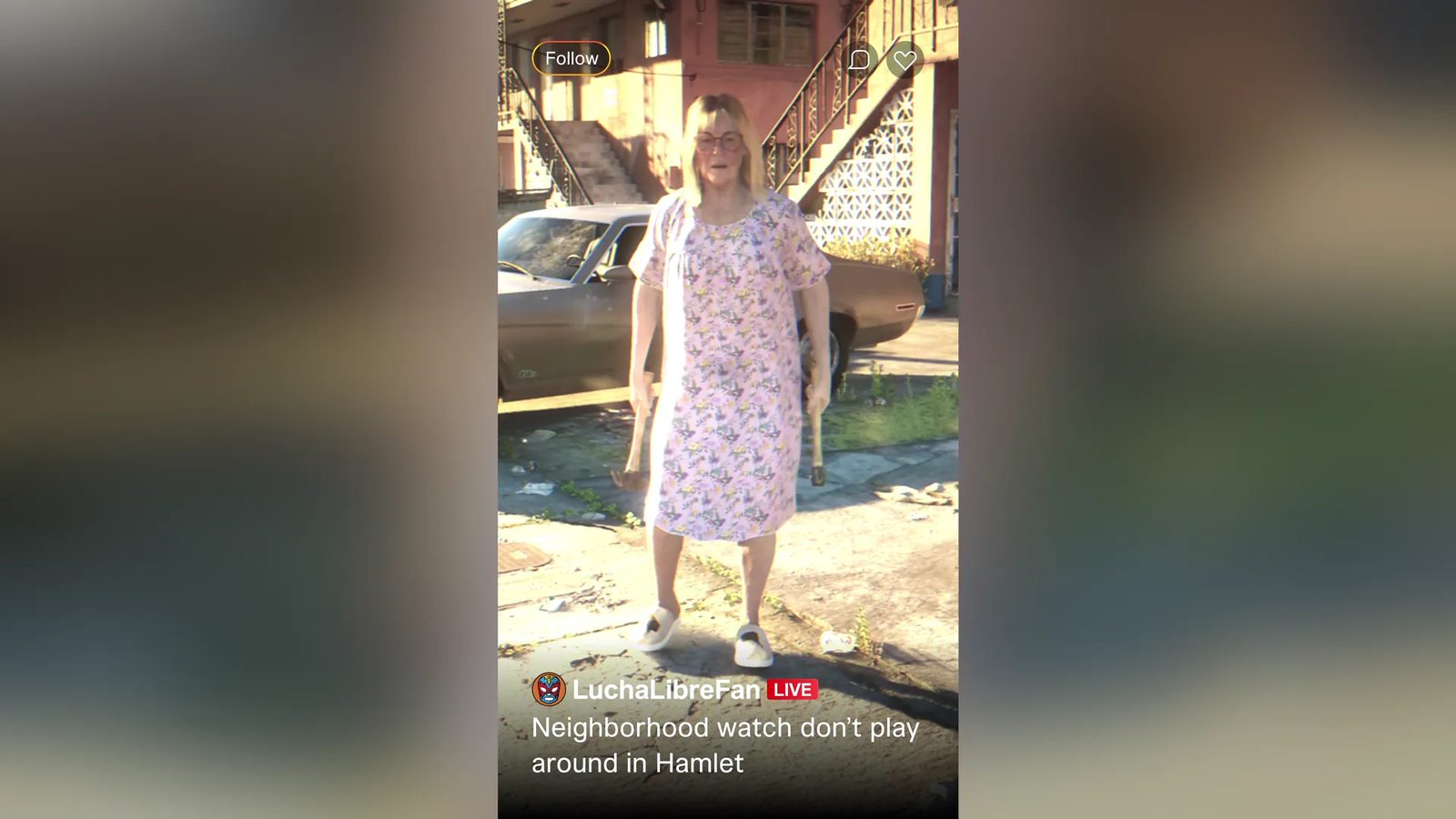 An older woman with blonde hair and glasses stands in a pink floral dress holding two hammers, in front of a parked car and a pink apartment block.