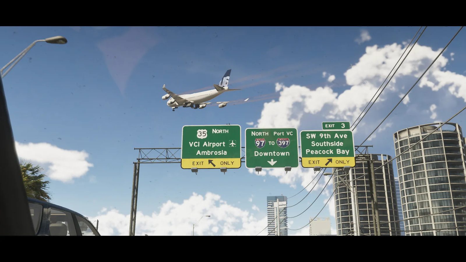 A white jet airliner flies low over a highway in Vice City, above green exit signs for VCI Airport, Downtown and Peacock Bay, with tall towers beside it.