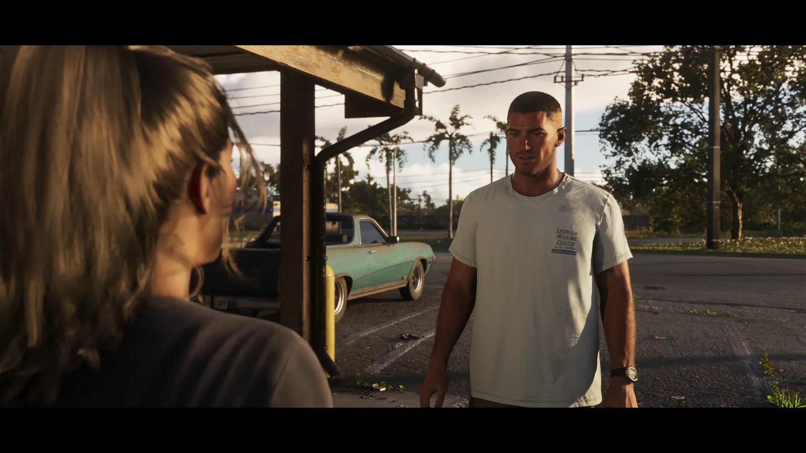 A short-haired man in a pale shirt faces a woman seen from behind, in a car park with a battered green car and palm trees at golden hour.