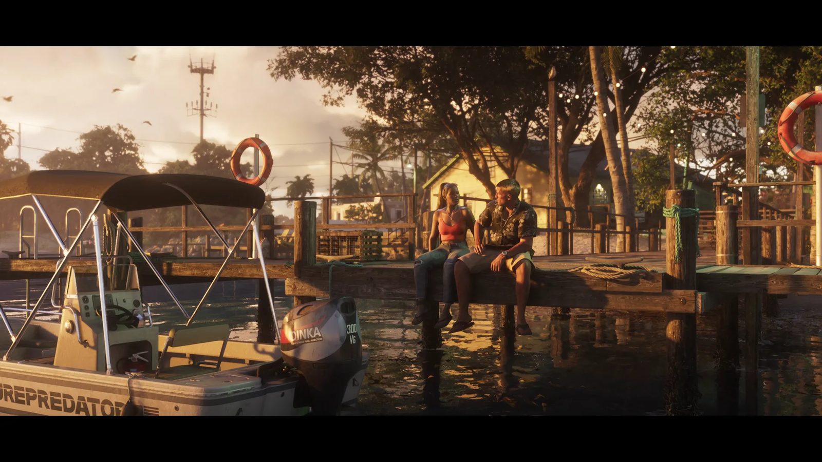 A man and a woman sit on the edge of a wooden jetty at sunset beside a moored boat in the Leonida Keys.