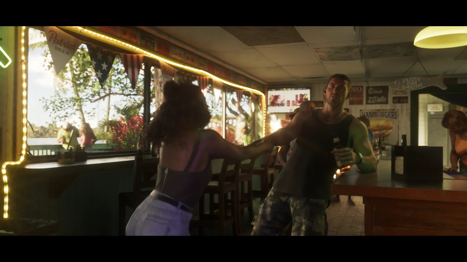A woman with dark curly hair pushes a muscular man in a tank top and camouflage shorts inside a waterside bar hung with bunting and fairy lights.