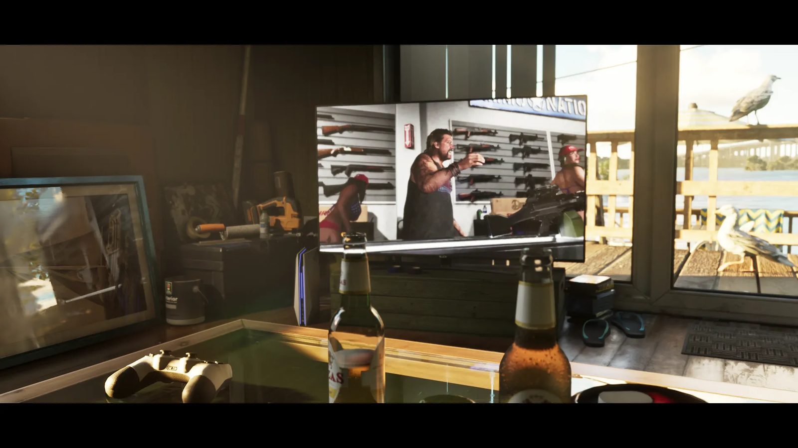 A television in a sunlit waterside room shows a bearded man in a gun shop, with two beer bottles and a games controller on a glass table in front.