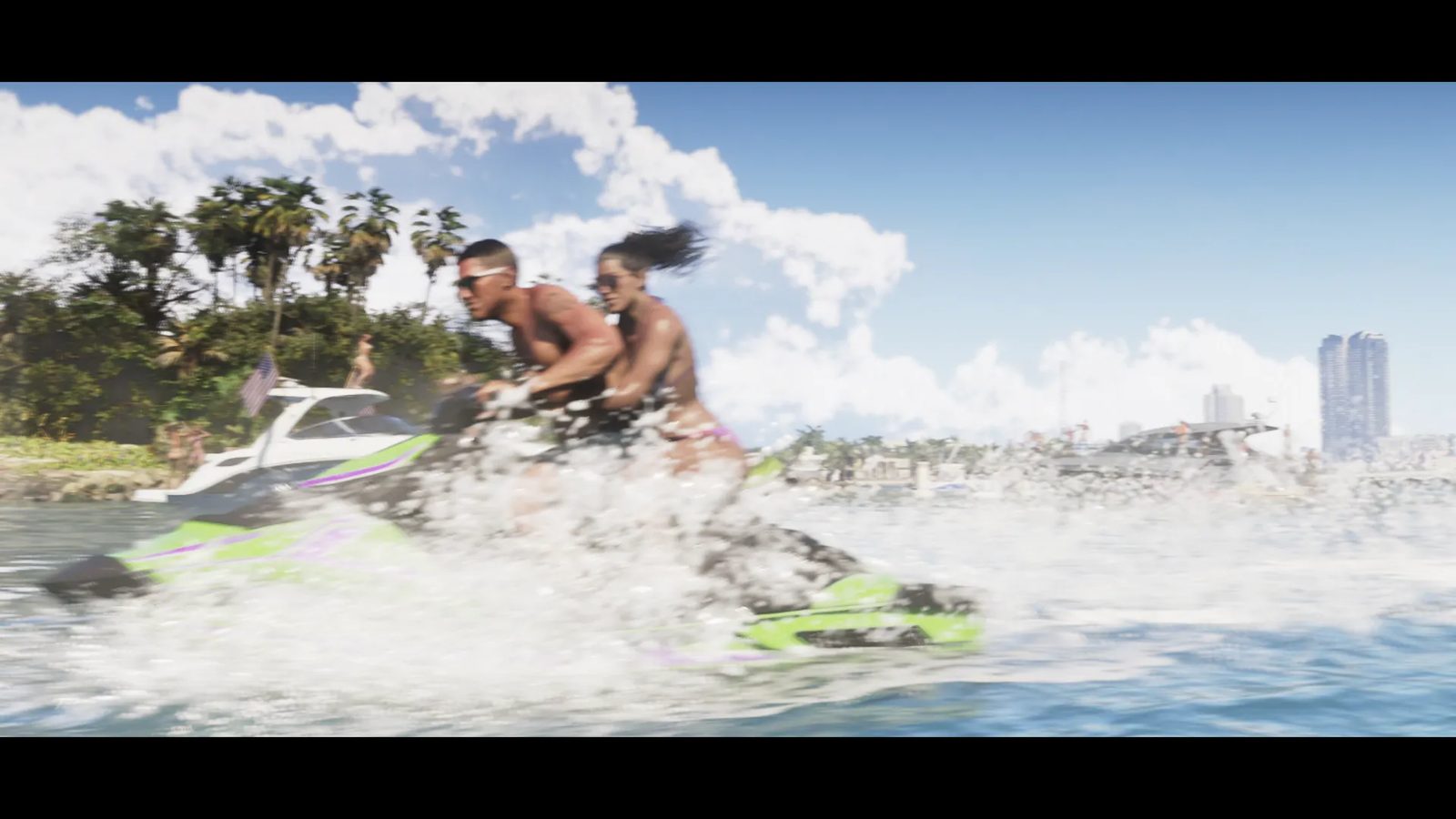 Jason Duval and Lucia Caminos ride a green and purple Shasa jet ski, throwing up spray, with a white boat and palm-lined shore behind.