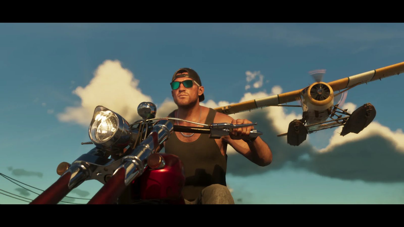 A man in green mirrored sunglasses and a backwards cap rides a red LCC Avarus motorcycle as a yellow Mammoth Dodo seaplane flies low behind him.