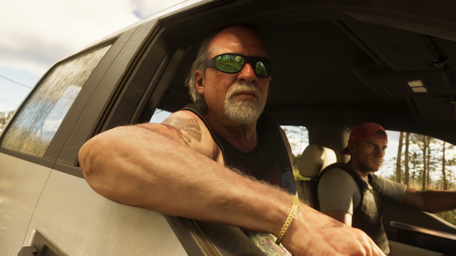 Brian Heder, an older man with a white goatee and green mirrored sunglasses, leans out of a dusty truck window while Jason Duval sits beside him.