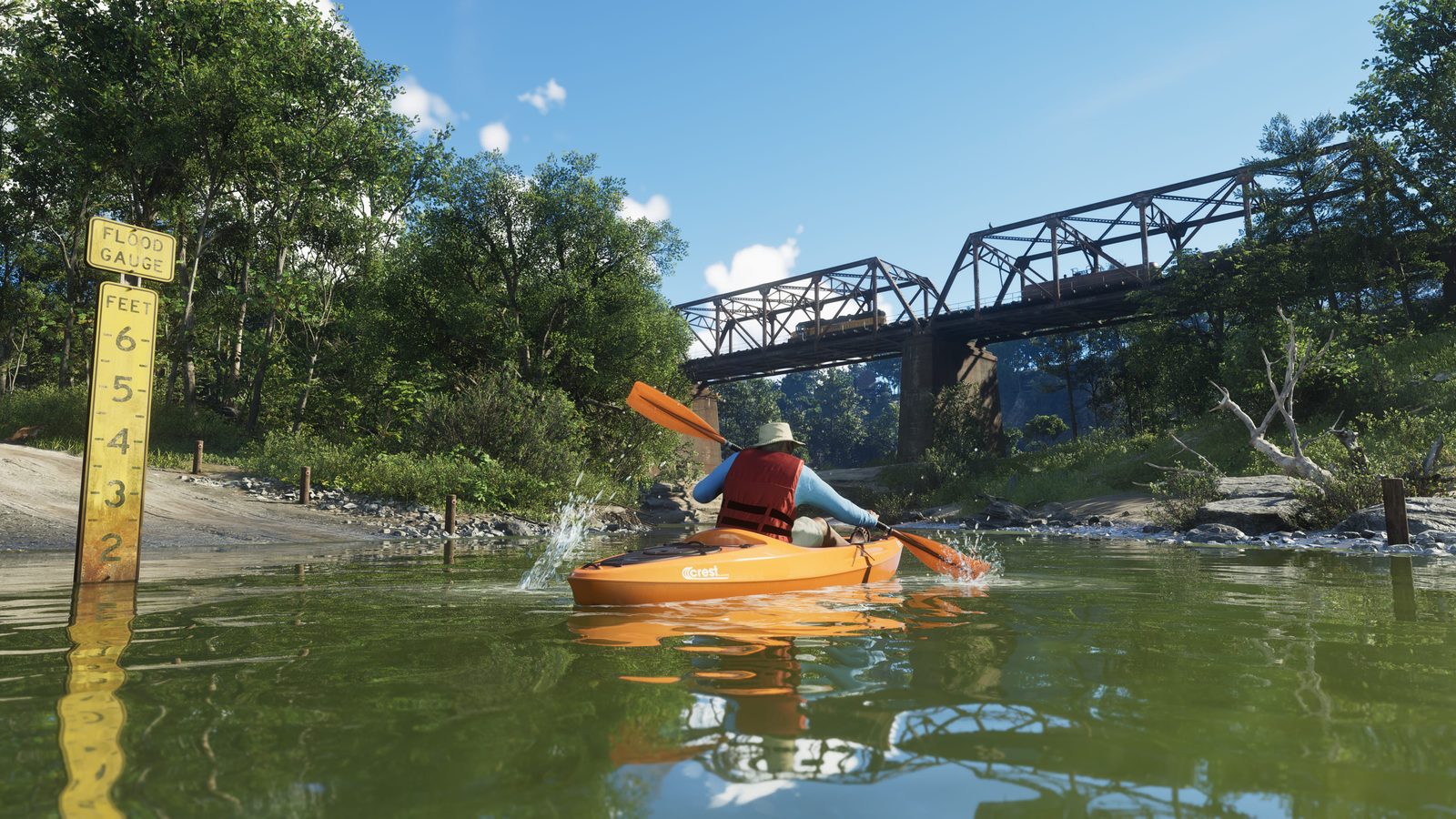 A kayaker in a red life jacket and hat paddles an orange Crest Kayak along a green river towards a steel railway bridge, with a flood gauge at left.