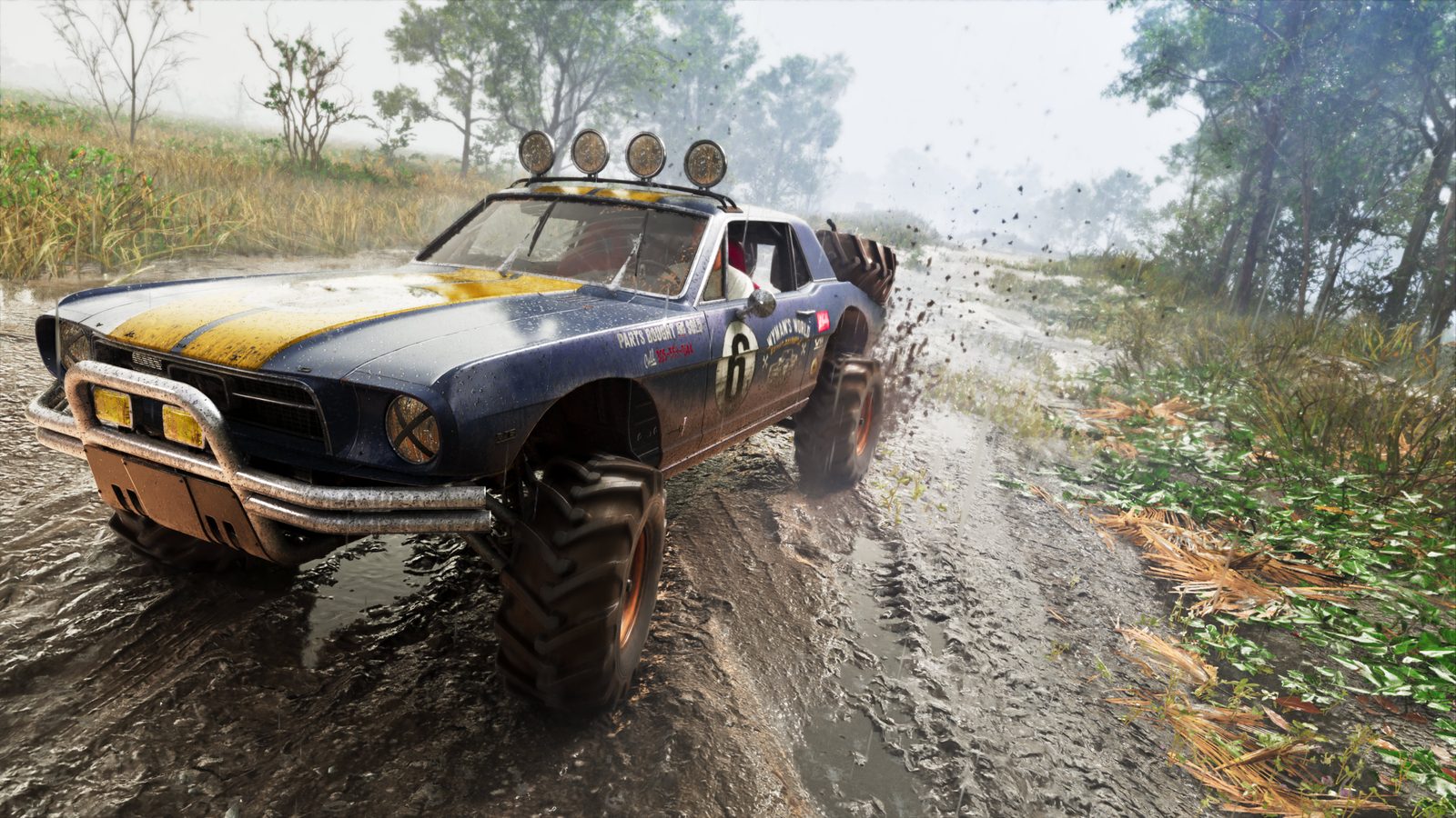 A muddy blue and yellow '67 Vapid Dominator Buggy with big tyres and roof lights sprays mud along a wet track beside trees and long grass.