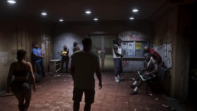 A man seen from behind faces a group of people in a dim, graffiti-covered outdoor passage with a notice board and glass doors.