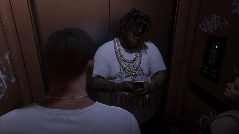 A heavyset man with gold chains and tattoos checks a phone in a dim, graffiti-covered lift, with a man seen from behind in the foreground.