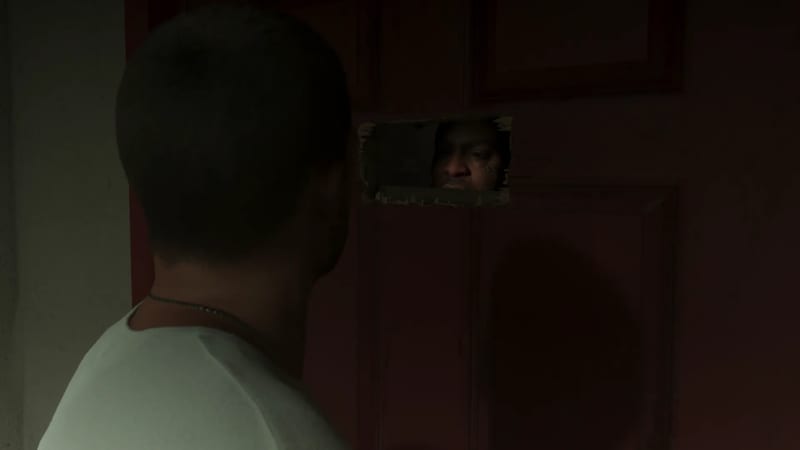 A man in a white t-shirt, seen from behind, faces a dark red door with a rough hole in it, through which another man's eyes can be seen.