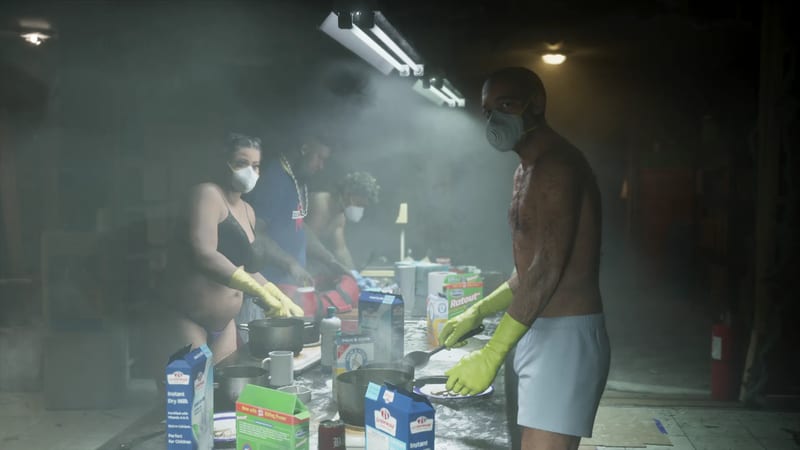 Four people in face masks and yellow rubber gloves work at a cluttered table of pans and cartons in a smoky, dimly lit room.
