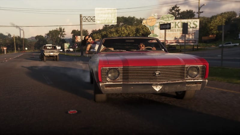 Lucia Caminos leans out of a red convertible driven by Jason Duval on a road past a Tucker's Citrus Farm billboard, with a pickup behind.