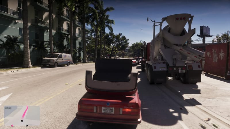 A red convertible with its roof folded down drives along a sunny palm-lined street in Vice City behind a white cement mixer truck, with a van parked on the left.