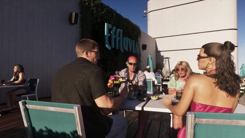Four people talk around a white table on a sunny rooftop terrace beneath a teal Effluvia sign, with teal chairs and a woman seated alone behind them.