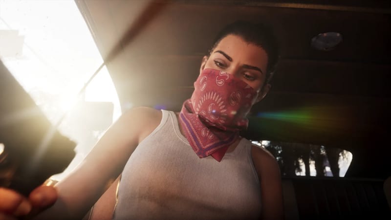 Lucia Caminos, wearing a red paisley bandana over her face and a white vest, sits in the back of a car holding a gun in bright sunlight.