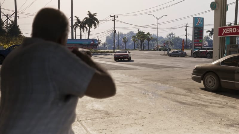 A man seen from behind aims a handgun across a sunlit Xero petrol station forecourt towards a red and white car on the road, with palm trees beyond.