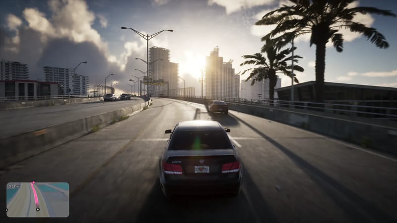 A dark grey saloon car drives along a raised road towards tower blocks, with palm trees and a low sun behind them, in Vice City.