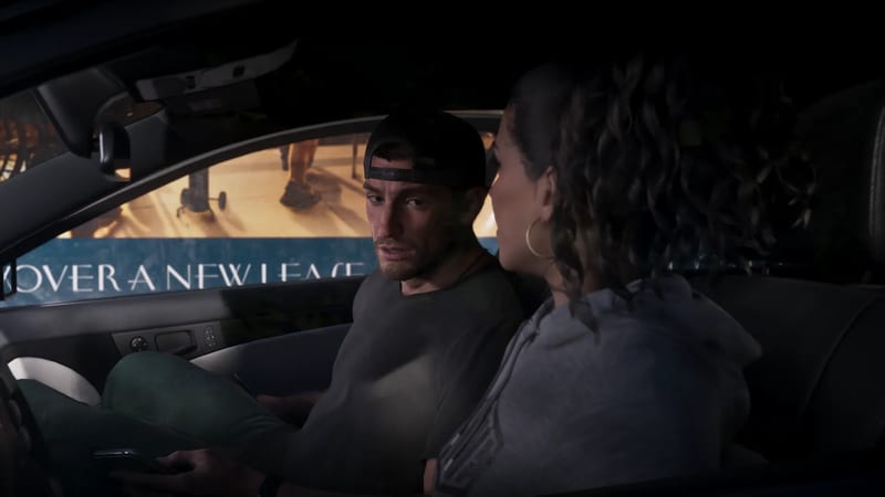 Jason Duval, in a backwards cap and grey t-shirt, looks across at Lucia Caminos in a grey hoodie as they sit in a car at night.