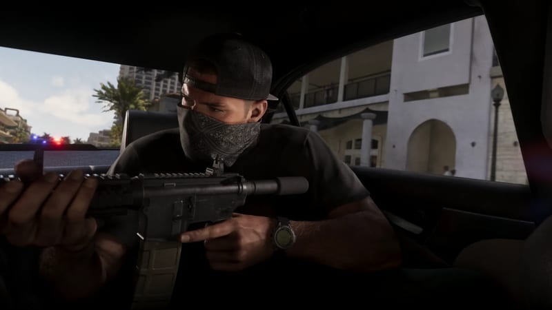 A masked man in a backwards black cap aims a suppressed rifle from inside a car, with police lights flashing down a sunny street behind him.