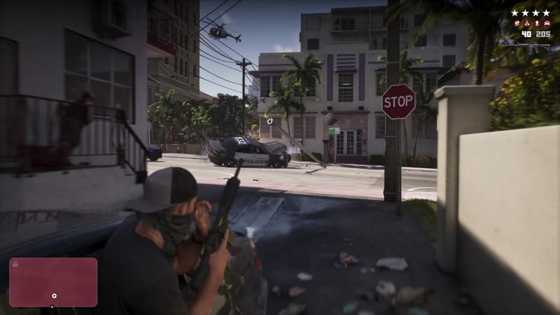 A masked man in a cap crouches behind a car holding a rifle, aiming at a crashed police car on a sunny street with a helicopter overhead.