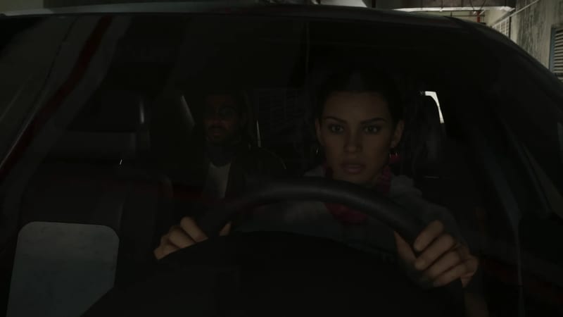 Lucia Caminos grips the steering wheel of a car in a dim concrete car park, looking wide-eyed, with a man in glasses sitting behind her.