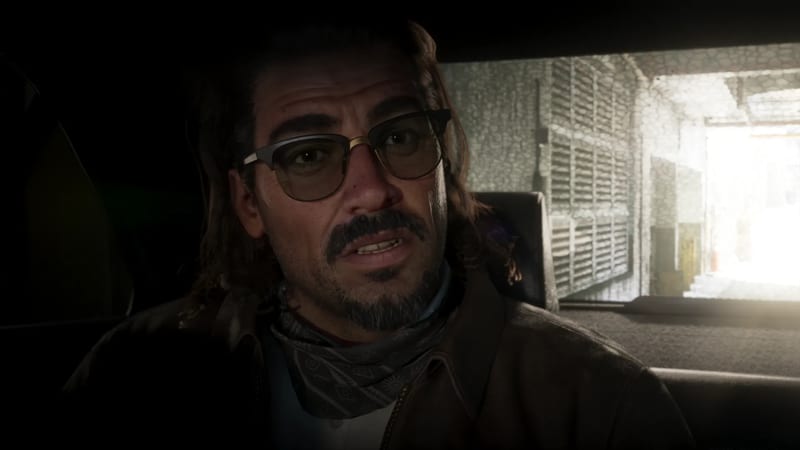 Raul Bautista, a man with a moustache, goatee and tinted glasses, looks ahead from inside a dim car, with a bright alley behind him.