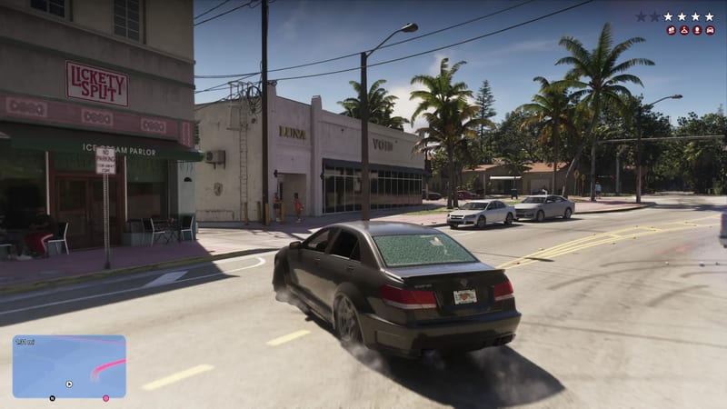 A dark grey saloon car drifts round a sunny street corner in Vice City, past an ice cream parlour and palm trees, with a four-star wanted level.