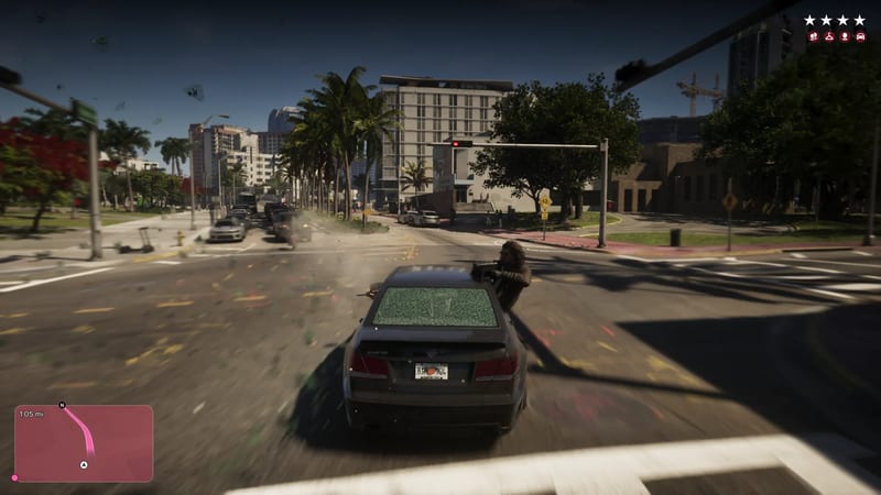 A man leans out of a dark saloon car with a shattered rear window, aiming a weapon as it speeds through a junction lined with palm trees in Vice City.