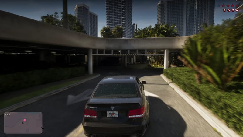A black Schafter saloon drives towards a concrete car park ramp in Vice City, with tower blocks and palm trees behind, under a clear sky.
