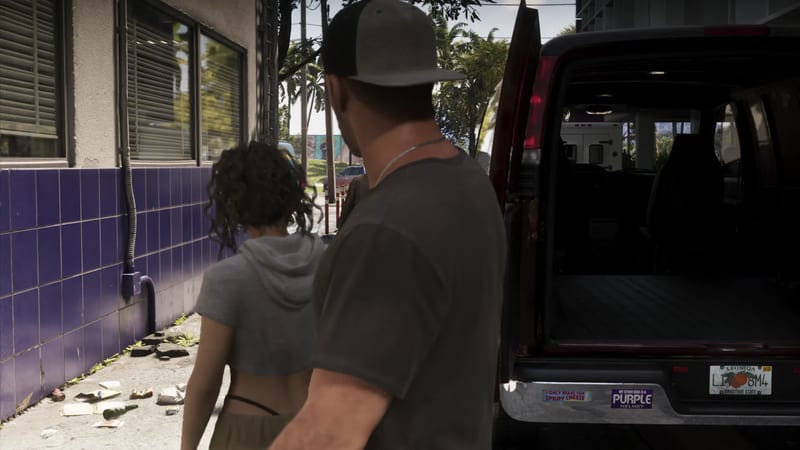 A man in a grey cap and a curly-haired woman walk past a purple-tiled wall towards a dark red van with its rear doors open on a sunny street.