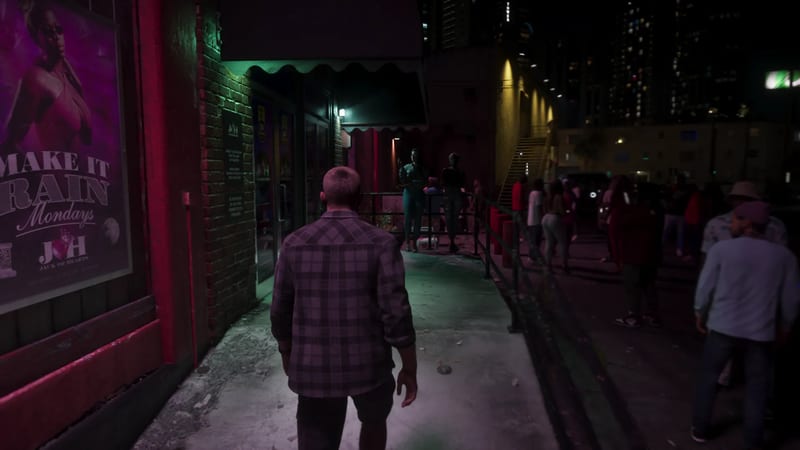 A short-haired man in a plaid shirt walks along a neon-lit night pavement past a Jack of Hearts poster, with a crowd queuing beside a railing.