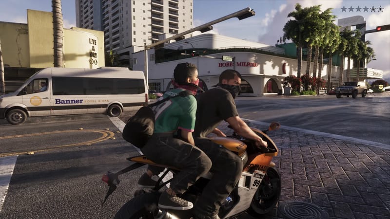 Two masked people ride a orange and white motorbike through a sunny city junction, with a Banner Hotel & Spa van behind them.