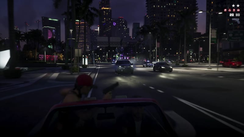 A man in a red cap aims a pistol from the back of a red pickup as cars with headlights chase through Vice City at night.