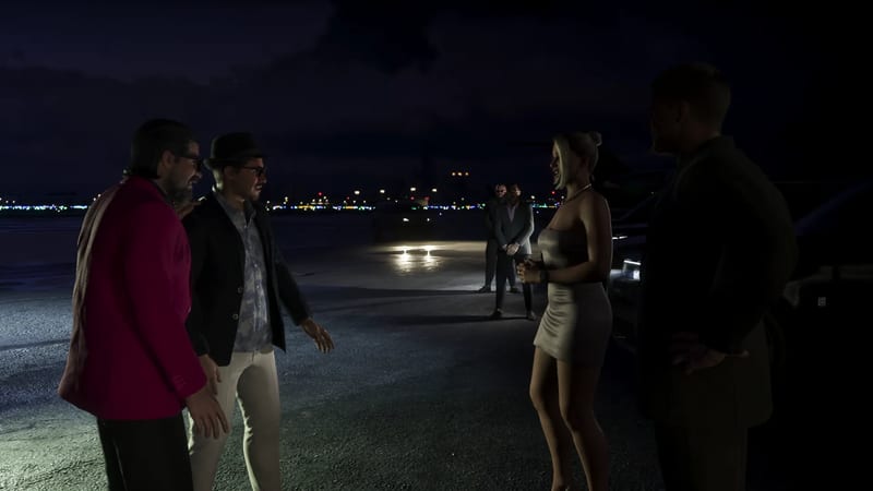 Two men in jackets greet a laughing blonde woman in a silver dress on a dark airport apron at night, with two men in suits standing behind.