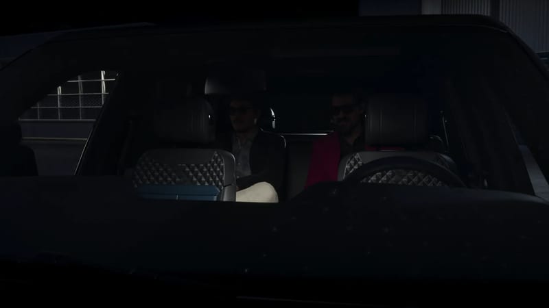 Two men in sunglasses sit in the back seat of a dark vehicle with diamond-stitched leather seats, seen through the windscreen at night.